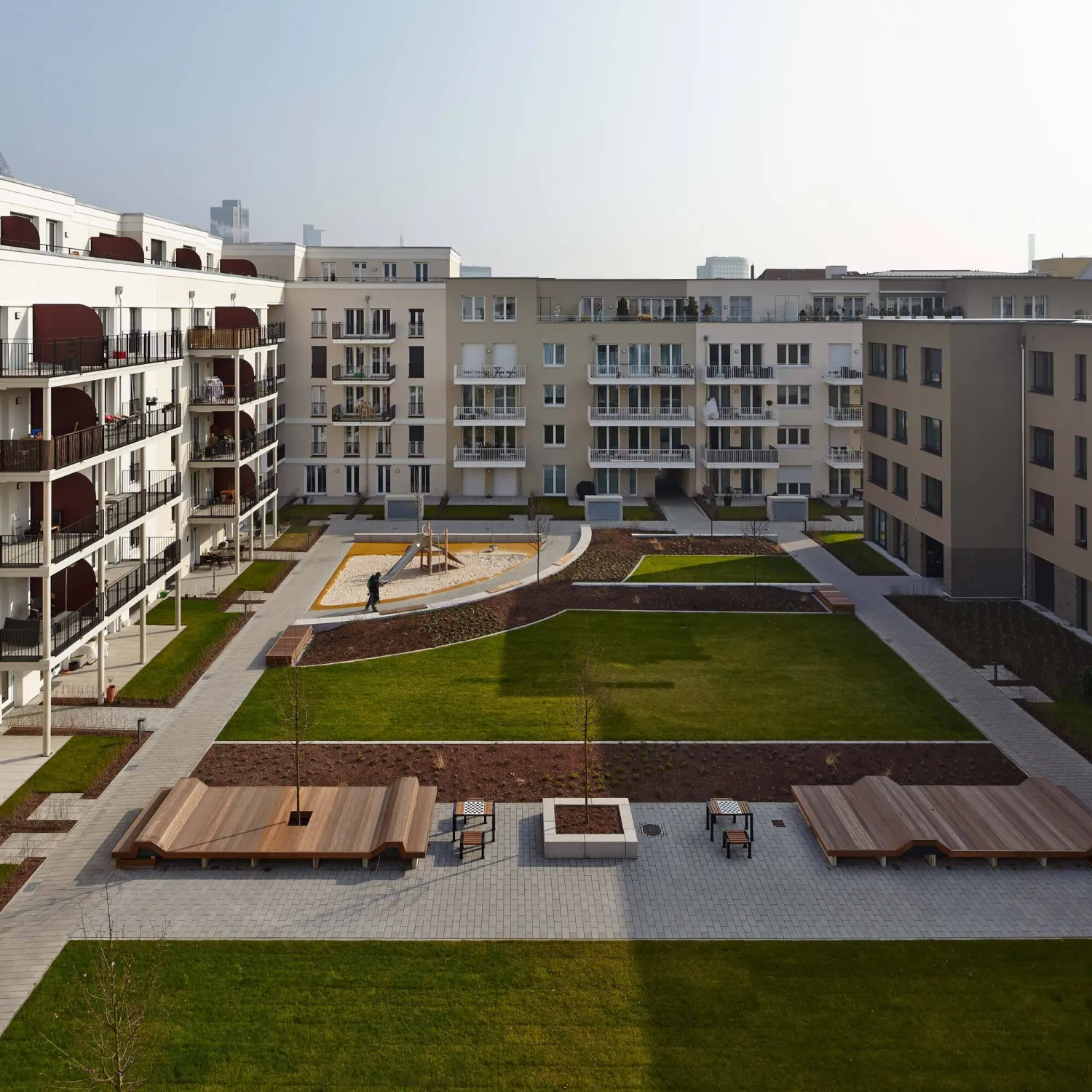 FRANK Quartier Frankenallee: ruhiger Innenhof mit Sitzbänken und Grünflächen als Oase im städtischen Umfeld.